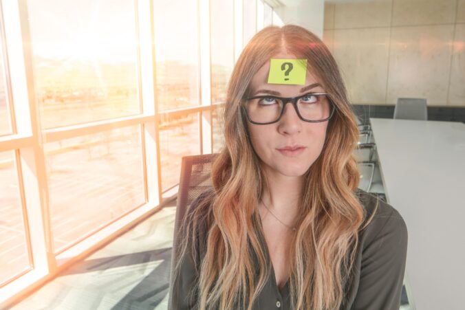 Kvinde på kontor med post-it i panden med spørgsmålstegn som billede på forvirring over, om ekstrovert/introvert er relevant at bruge om jobkompetencer